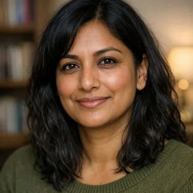 South Asian British woman, mid-40s, black wavy hair, warm expression, olive knit sweater